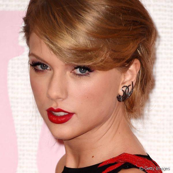 Taylor Swift usou delineador preto no formato gatinho para marcar os olhos e escolheu um tom claro de vermelho alaranjado para os l?bios